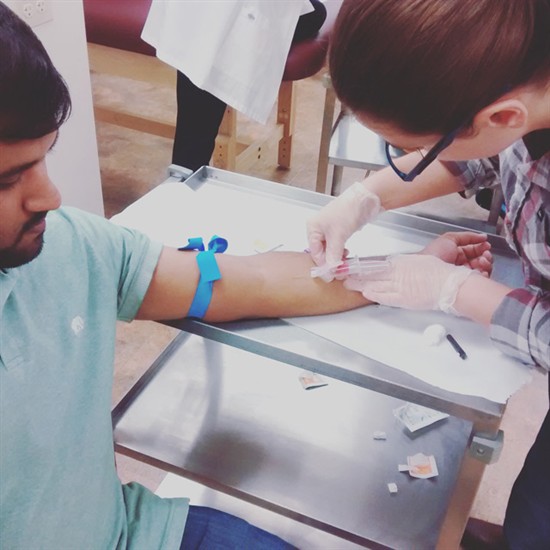 NUHS student performing phlebotomy in clinic