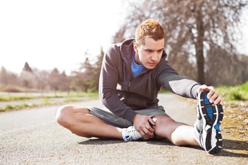 man sitting on ground stretching leg