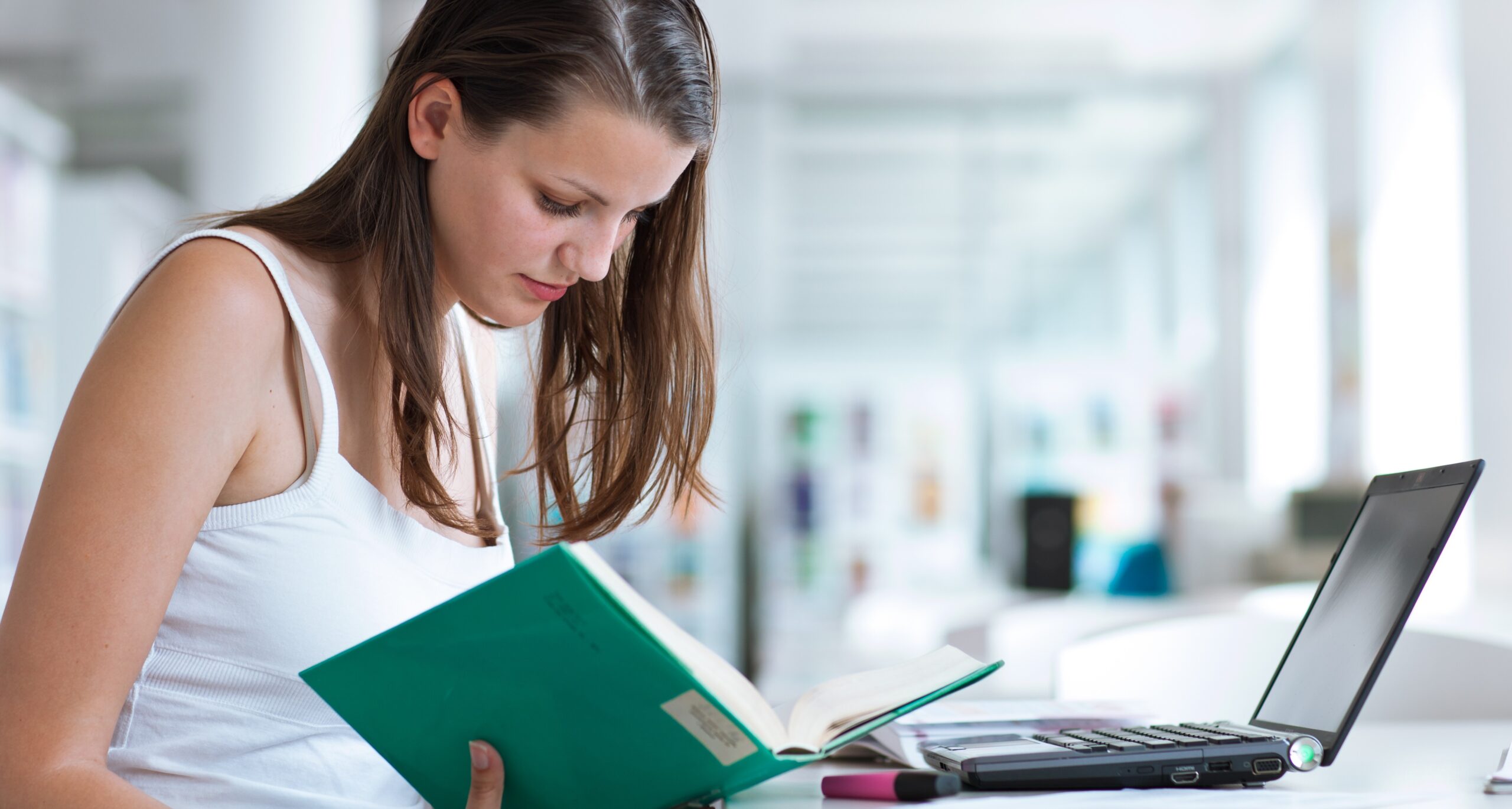 Female student with laptop studying in library