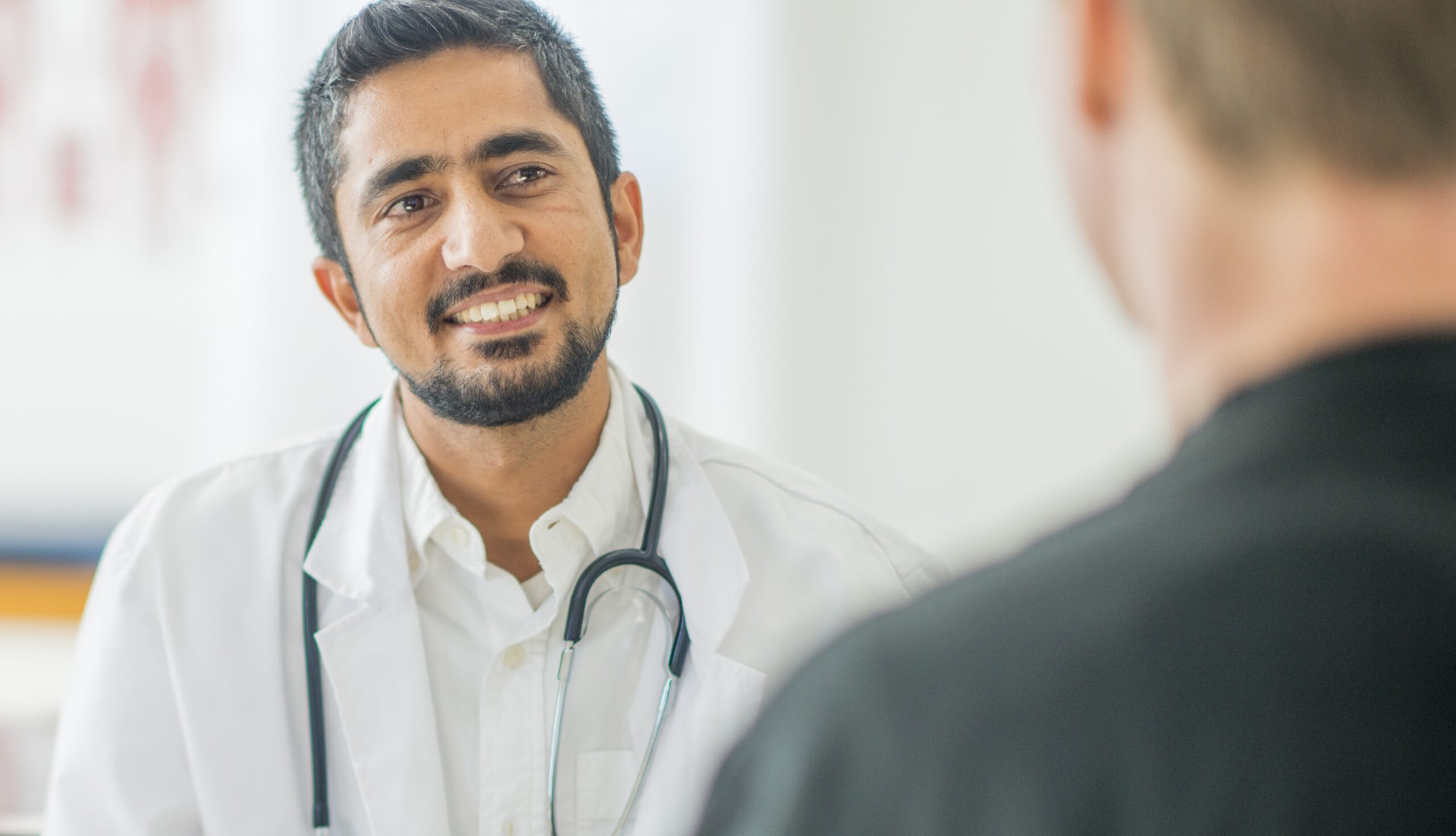 Male intern conferring with male patient in medical office