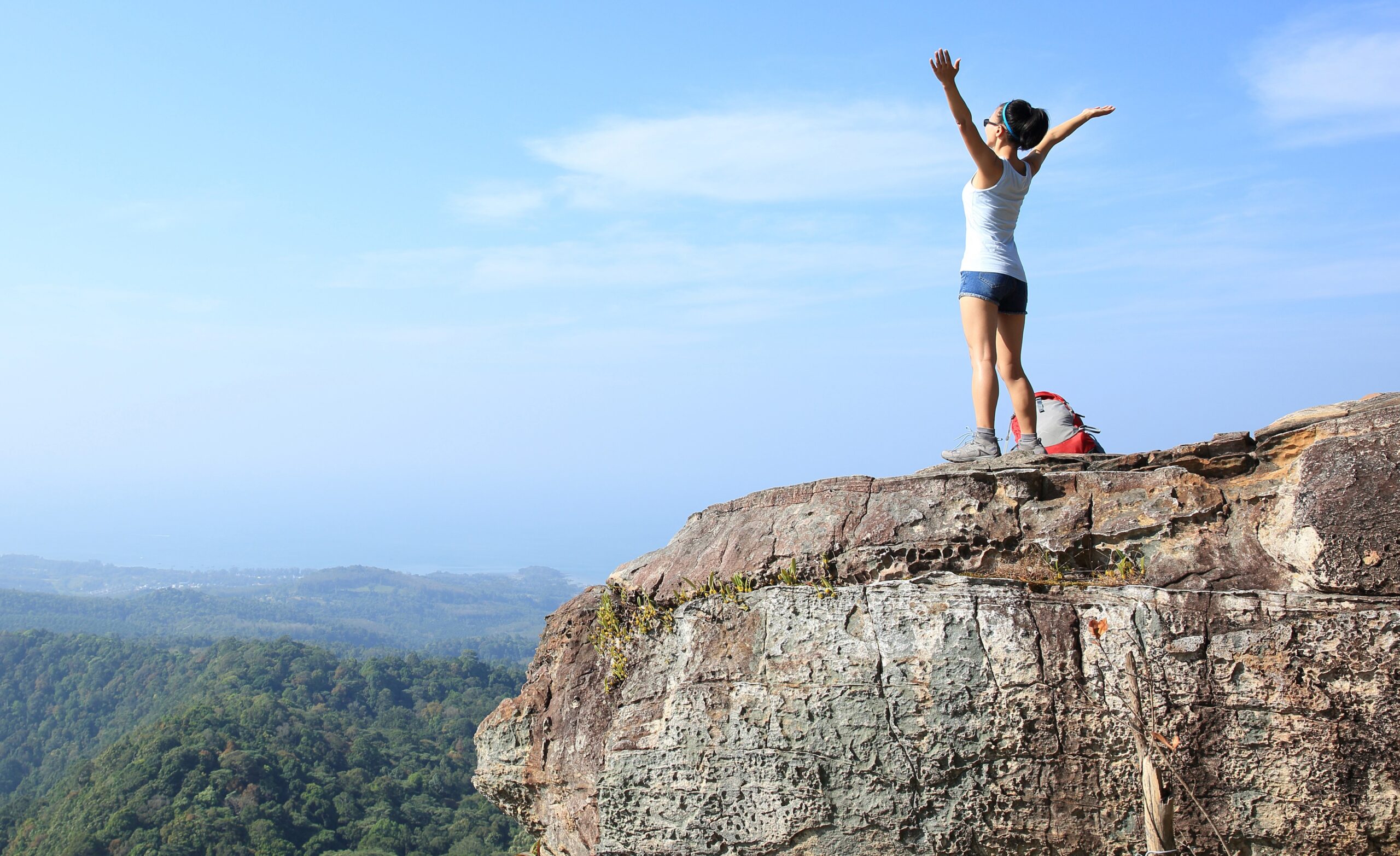 Female hiker overcomes challenge at mountain summit.