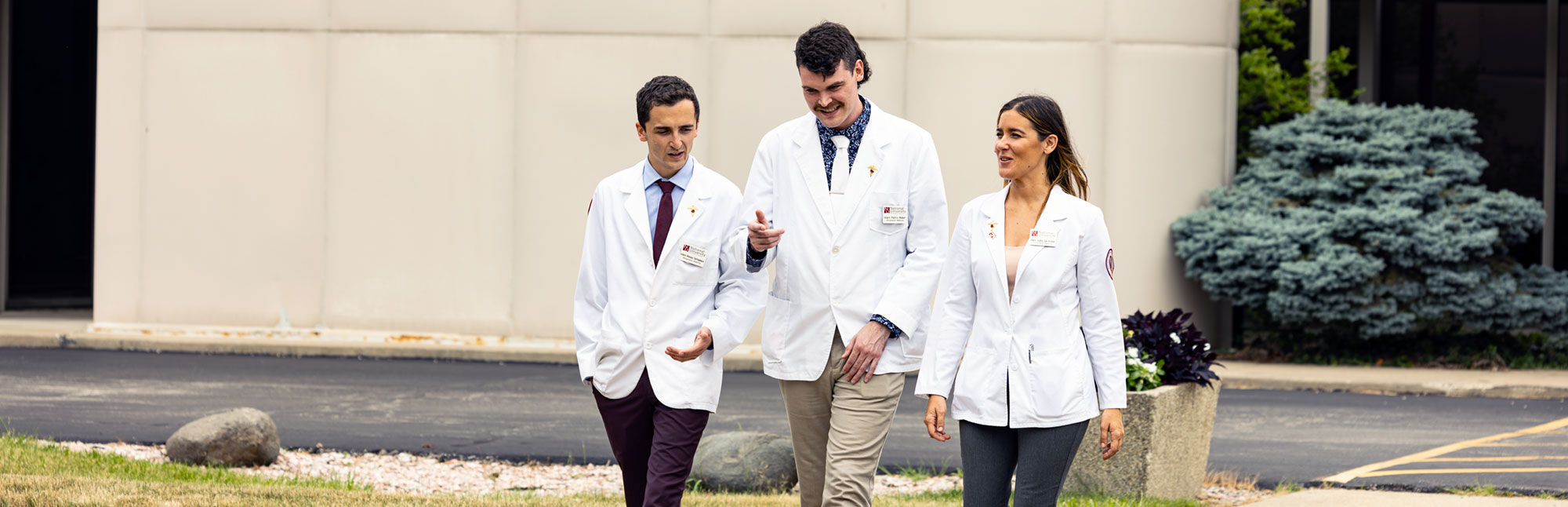 NUHS interns wearing white coats walking outside