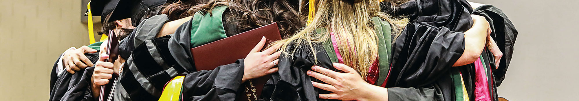 NUHS graduates hugging in cap and gowns