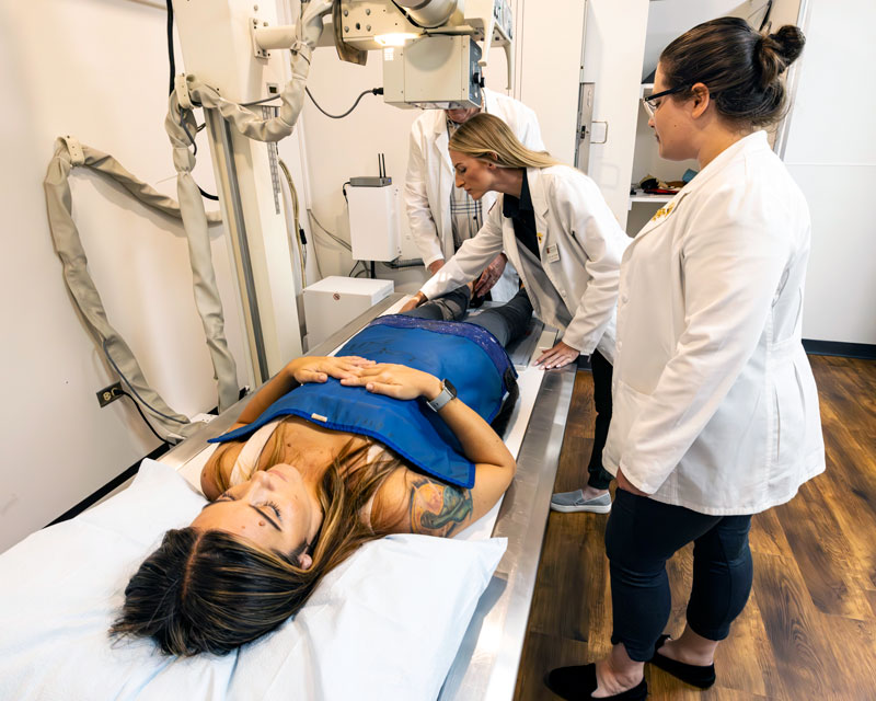 students prepping volunteer for x-ray imaging