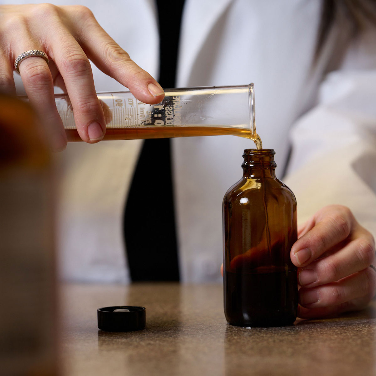 student pouring mixture in naturopathic dispensary