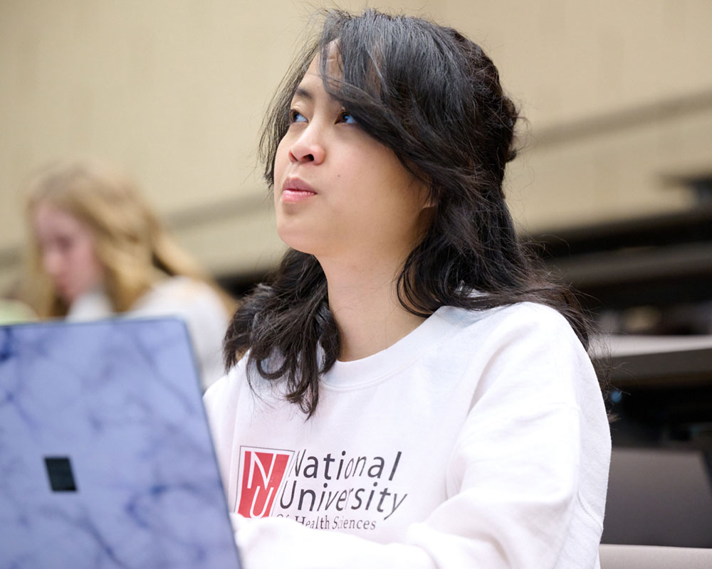 student in lecture hall wearing NUHS sweatshirt