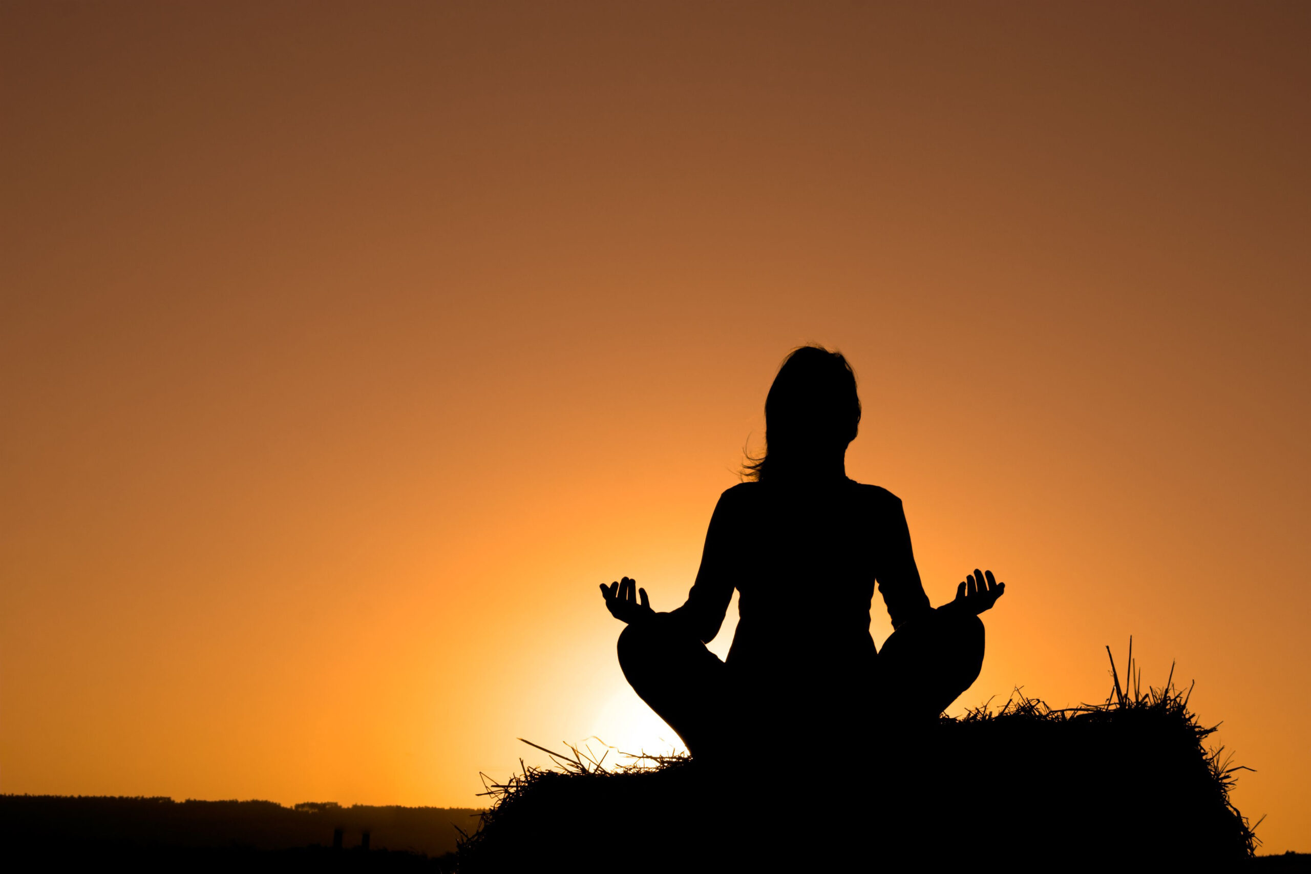 Sunset silhouette of woman meditating